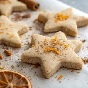 Gros plan sur biscuits sablés sans sucre, texture sablée dorée et épices d’hiver.
